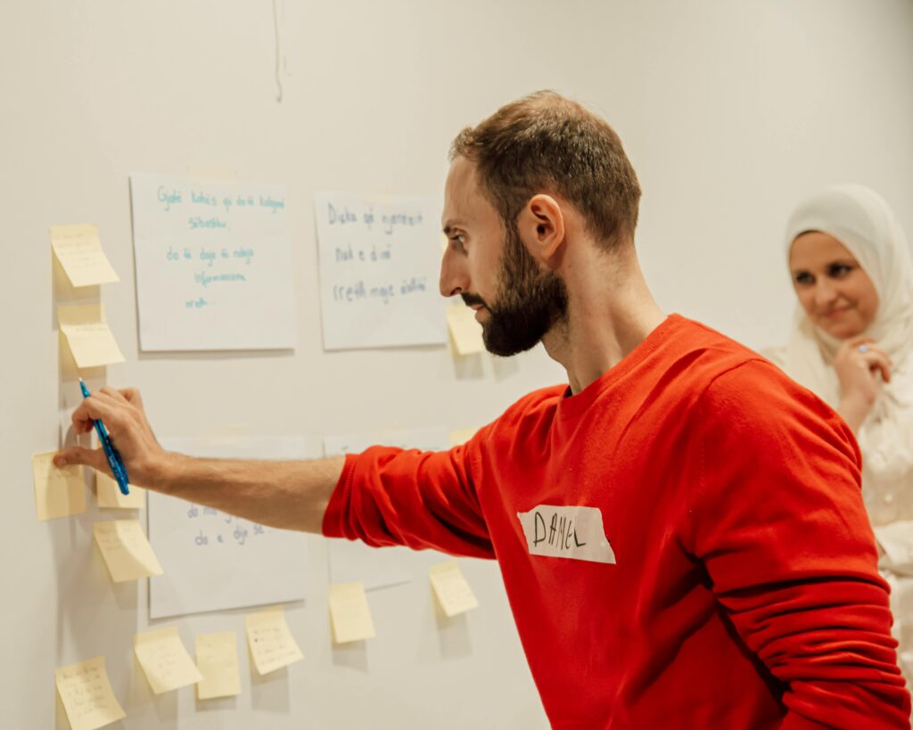 Man and woman collaborating with sticky notes on a wall during a creative session.